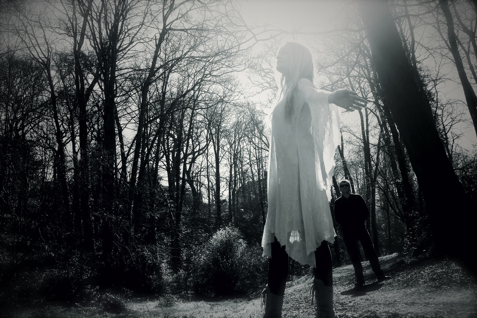 Sophie in a white dress among bare trees, Jonny behind her
